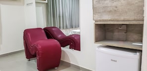Una habitación con dos sillones de masaje, una mesita y un armario blanco.
