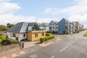 A residential street with modern houses, a clear sky, and a well-maintained road. - Luxury 2-Bed Coastal Apartment with Sea Views, Balcony & Dedicated Parking (Worthing)