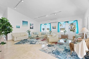 A spacious living room with a beige sofa, a glass coffee table, and a blue patterned rug. - Cielo y Mar Beach House | Direct Beach Access (Humacao)