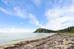 A beach with a clear sky, calm sea, and a distant hill with vegetation. - Cielo y Mar Beach House | Direct Beach Access (Humacao)