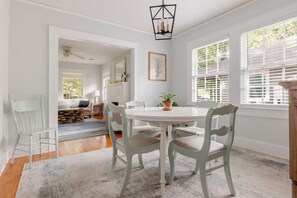 A dining area with a white table and chairs, a potted plant, and a fireplace. - Quaint little cottage nestled in the heart of East Hill! (Pensacola)