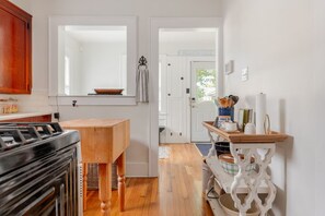 Une cuisine avec une table en bois, un poêle et une fenêtre au-dessus de l’évier.