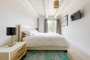 Ein Schlafzimmer mit einem Bett, einem Nachttisch, einer Lampe und einem Fernseher an der Wand.