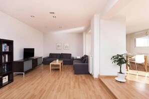 A modern living room with a sectional sofa, a TV, and a bookshelf. - Elegant Eixample Penthouse with Private Terrace & City Views (Barcelona)