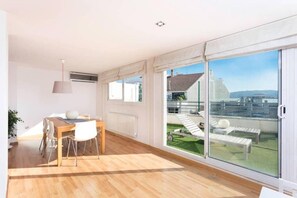 Eine moderne Wohnung mit Essbereich, großen Fenstern und Blick auf eine Grünfläche.