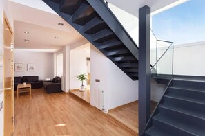 Ein modernes Interieur mit Treppe, Holzboden und Wohnbereich mit Möbeln.