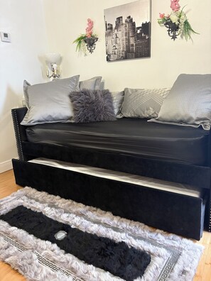 A black sofa with storage drawers, grey patterned pillows, and a black and white rug. - Girls Night Out Downtown New Orleans (New Orleans)