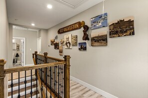 A hallway with a wooden staircase, a sign reading 'USS GALVESTON,' and various historical photographs on the wall. - Historic Borden Retreat: 2 Homes 6BR Hot Tub Sauna Pets OK (Galveston)