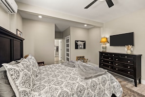 A bedroom with a bed, dresser, TV, and artwork. - Historic Borden Retreat: 2 Homes 6BR Hot Tub Sauna Pets OK (Galveston)