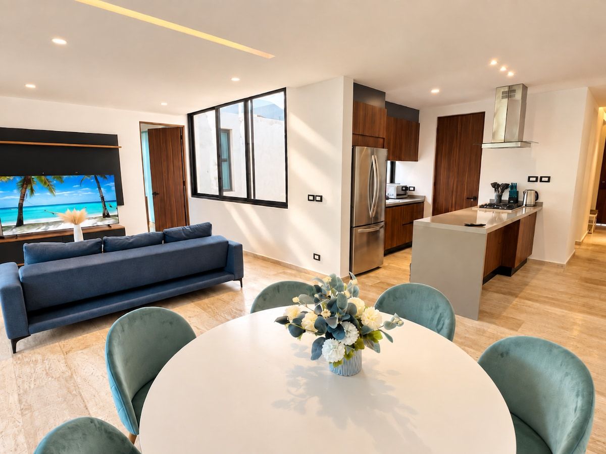 Ein modernes Wohnzimmer mit Essbereich, einer Couch, einer Küche und Blick ins Freie.