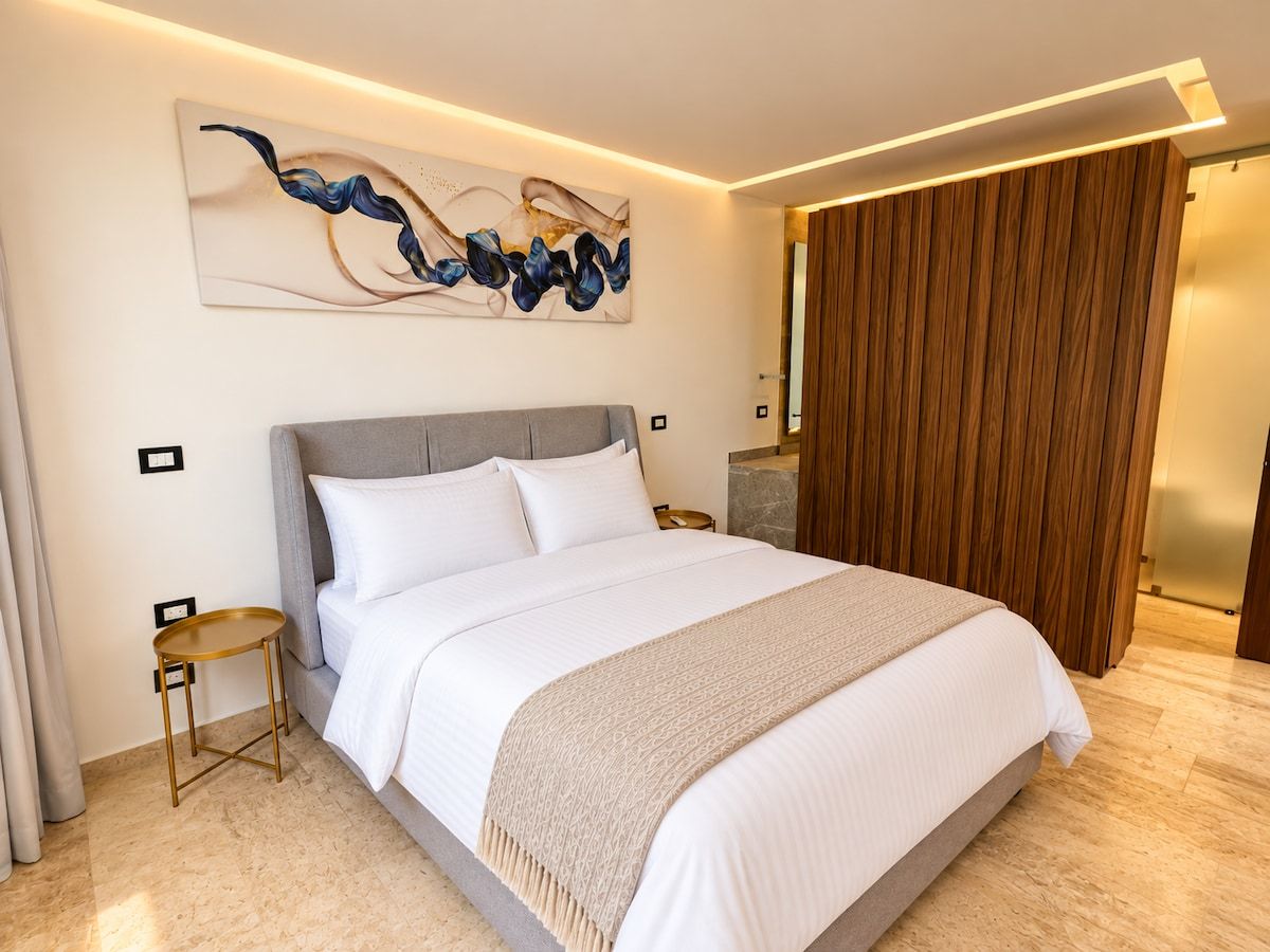Ein modernes Hotelzimmer mit einem großen Bett, einem kleinen Beistelltisch, einer Wanddekoration und einer Holzwand.