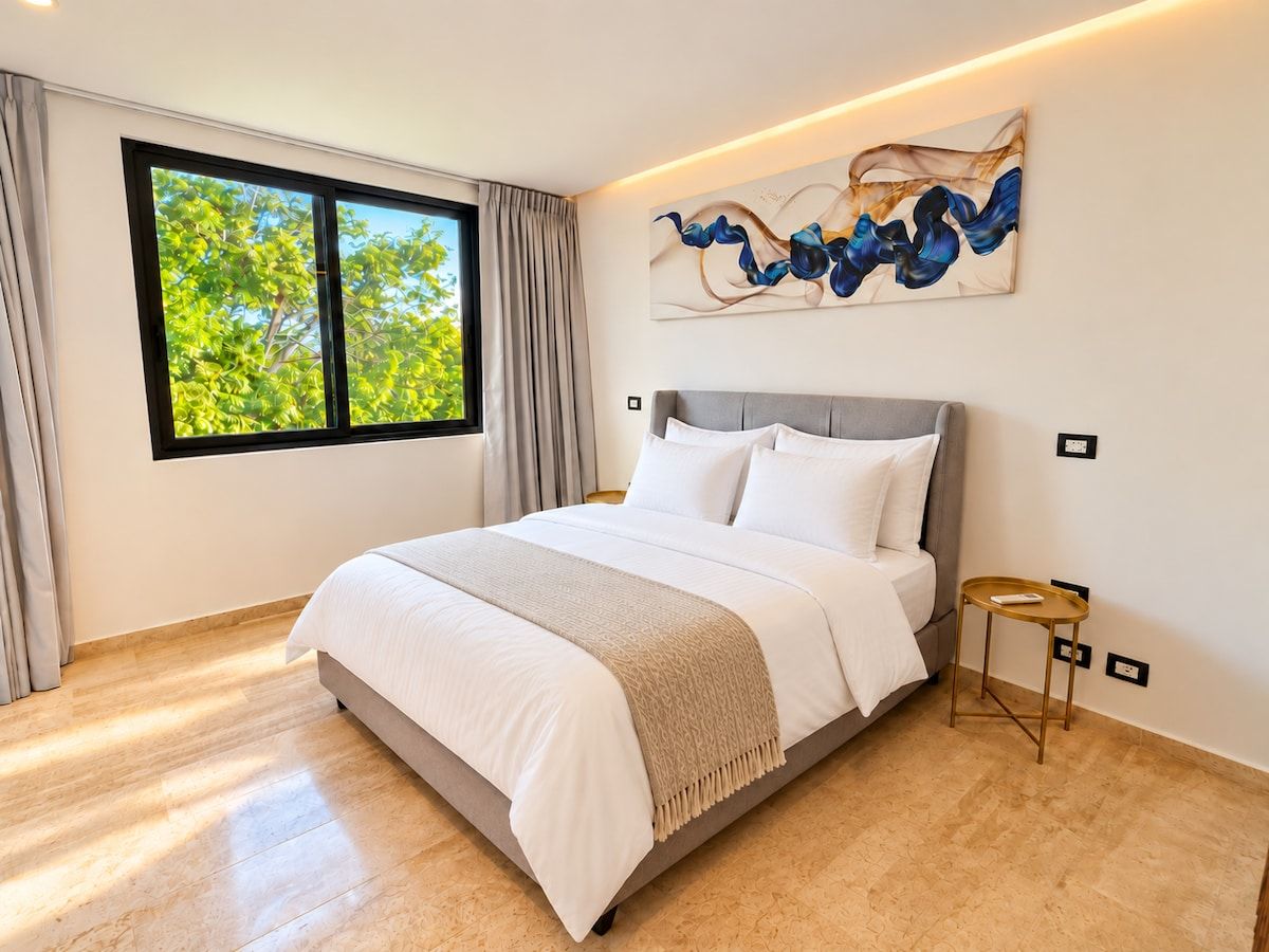 A modern bedroom with a large bed, a bedside table, and a window with curtains.