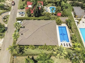 An aerial view of a resort with a large swimming pool, multiple red-roofed buildings, and lush tropical landscaping. - Super Modern 3bd/3.5ba Spacious Villa Private pool, Grill Hispaniola Residencial (Cabarete)