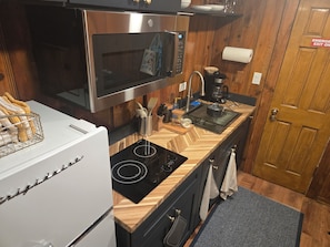 A compact kitchen with a microwave, stove, sink, and wooden countertop. - Cozy Hyde Park Greystone Garden-Level Suite near Obama Presidential Center (Chicago)