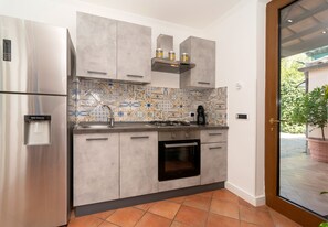A modern kitchen with stainless steel appliances, a patterned backsplash, and a view of the outdoors. - Relais Cacace by Espresso Rentals (Massa Lubrense)