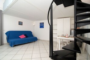 A room with a blue sofa, a white table with cups and a kettle, and a black spiral staircase. - Casa Melina by Espresso Rentals (Sant'Agata Sui Due Golfi)