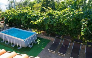 An outdoor swimming pool with a surrounding deck, a green lawn, and a dense hedge. - Villa Antolusa by Espresso Rentals (Priora)