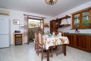 A kitchen with a dining table, chairs, a refrigerator, a stove, and a window with a view of greenery. - Villa Antolusa by Espresso Rentals (Priora)