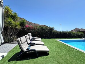 A poolside area with lounge chairs, a swimming pool, and a mountain backdrop. - EstrellaDelSur/OceanWiew/Heatpool/By Kalmacanaria (Mogán)