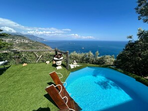 A swimming pool with a clear view of the ocean and a grassy area with a wooden structure. - Villa Fontanarosa by Espresso Rentals (Massa Lubrense)