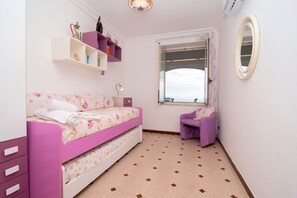 A bedroom with a pink bed, a desk, a window, and a shelf with decorative items. - Villa Fontanarosa by Espresso Rentals (Massa Lubrense)