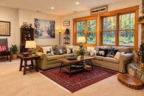 A cozy living room with a fireplace, large windows, and a variety of decorative pillows. - Private 4 Acres, Hot Tub, Fire Pit, 2 Mi to Snowshoe Entry (Cass)
