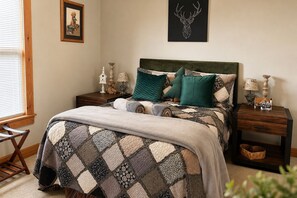 A bedroom with a bed, a headboard, a nightstand, a lamp, a framed picture, and a wall decoration. - Private 4 Acres, Hot Tub, Fire Pit, 2 Mi to Snowshoe Entry (Cass)