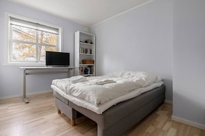A bedroom with a bed, a desk with a computer, and a bookshelf. - Tromsø 80 m² Apartment with balcony sea view (Tromsø)