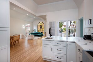 A modern kitchen with white cabinetry, a marble countertop, and a built-in sink. - Alta Vista Terrace By Alora Reserve (Los Angeles)