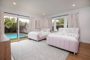 A bedroom with two beds, a pool, and a view of greenery. - Alta Vista Terrace By Alora Reserve (Los Angeles)