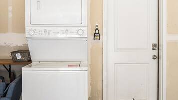 A laundry room with a washing machine and dryer, a door, and exposed ductwork.