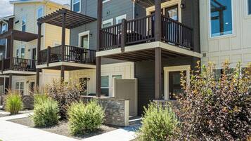 A modern multi-story residential building with a covered outdoor deck area.