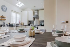 A modern kitchen with a dining area set for a meal. - Gemstone Diamond - Coop LIVE - Etihad - Free Parking - Pool table (Greater Manchester)