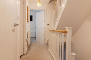 A hallway with white walls, a carpeted floor, a wooden handrail, and a door leading to another room. - Gemstone Diamond - Coop LIVE - Etihad - Free Parking - Pool table (Greater Manchester)