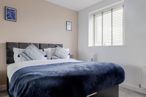 A bedroom with a bed, pillows, a window with blinds, and a radiator. - Gemstone Diamond - Coop LIVE - Etihad - Free Parking - Pool table (Greater Manchester)