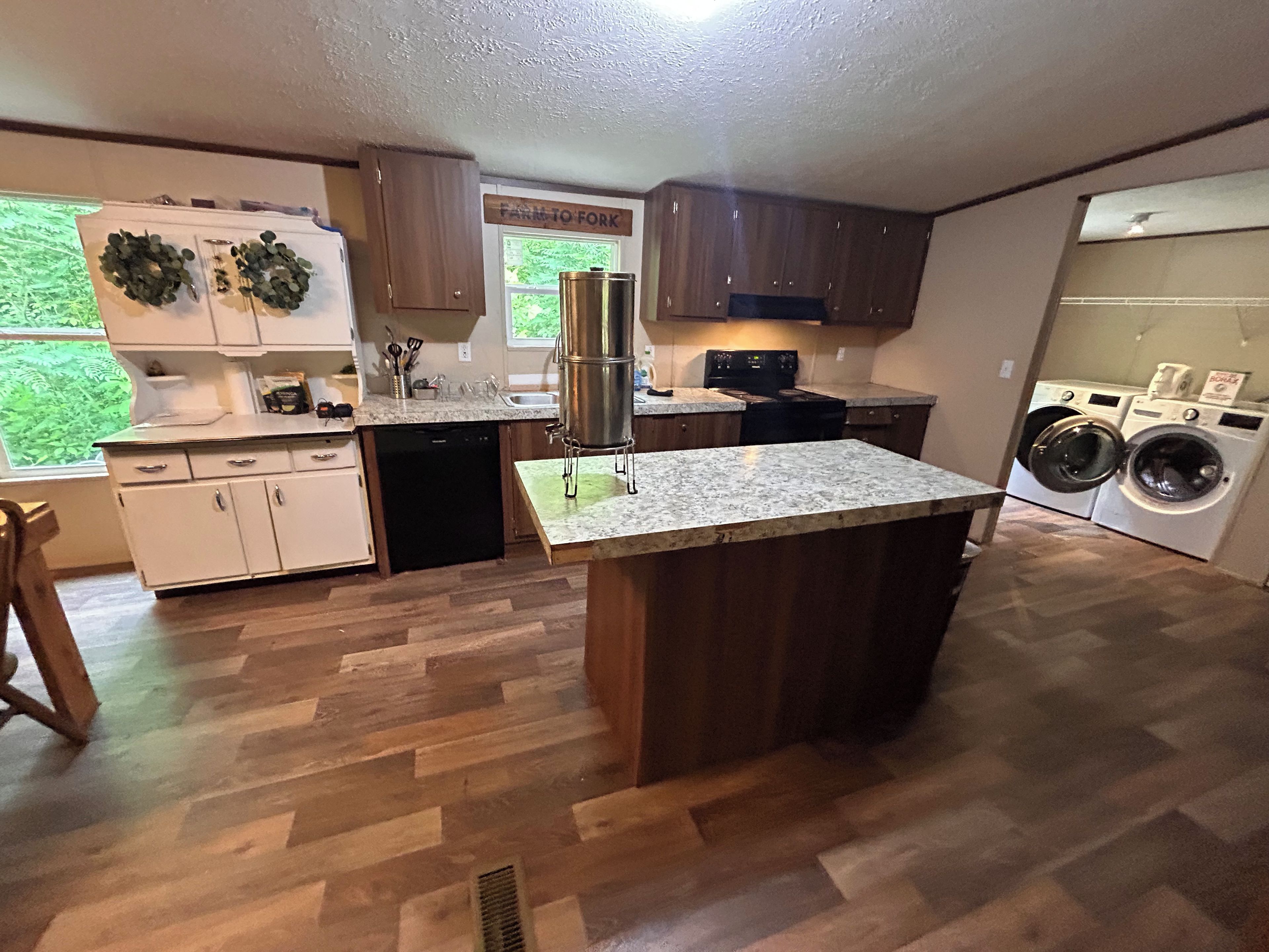A modern kitchen with wooden cabinets, a granite countertop, a built-in dishwasher, and a large island with a sink.