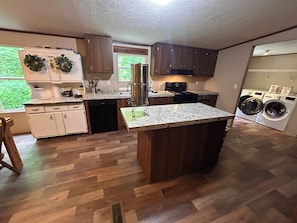 A modern kitchen with wooden cabinets, a granite countertop, a built-in dishwasher, and a large island with a sink. - 4 Bedrooms In Nature Only 35 Min. to Gatlinburg (Cosby)