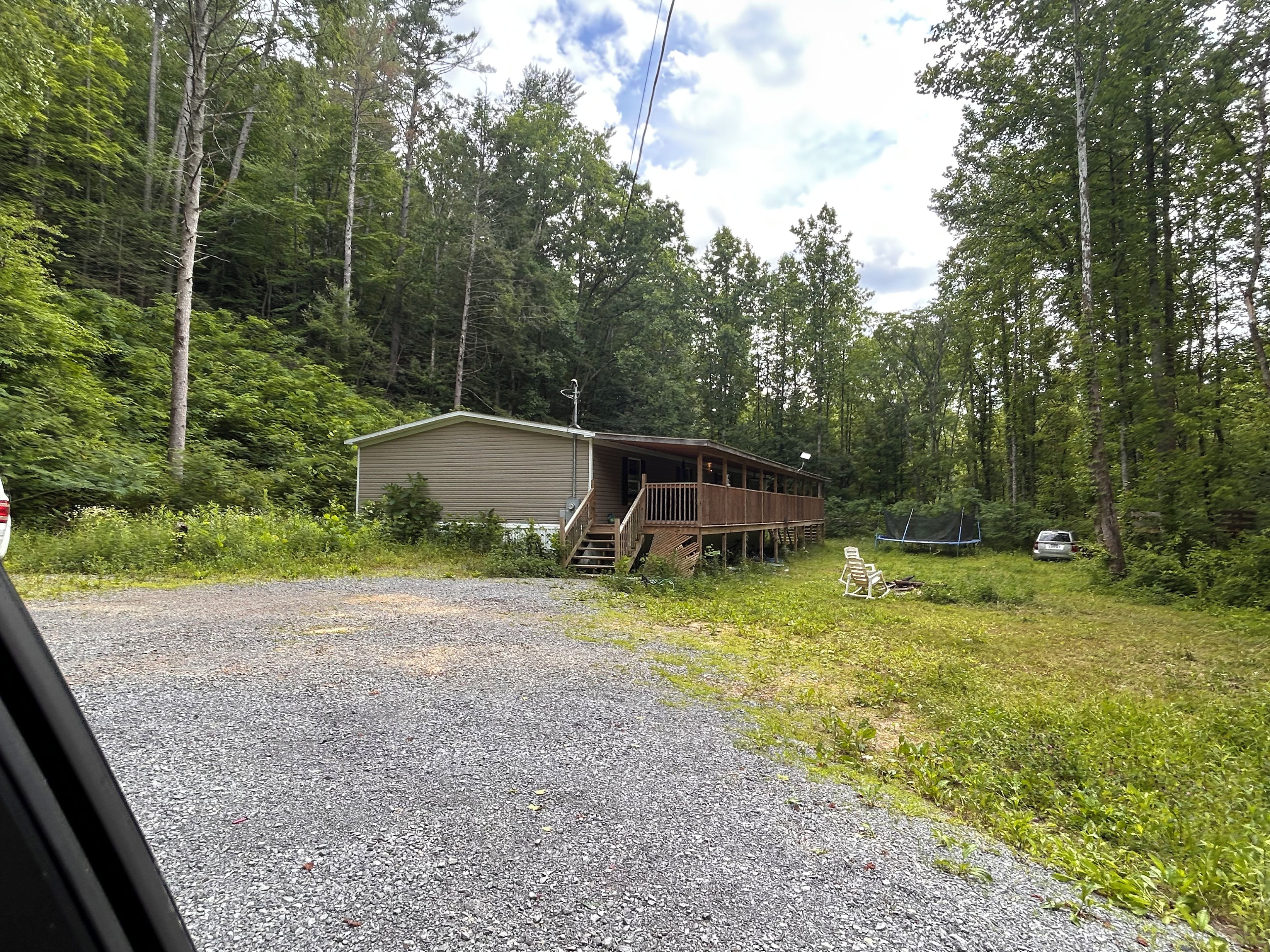 A cabin with a deck, surrounded by forest.