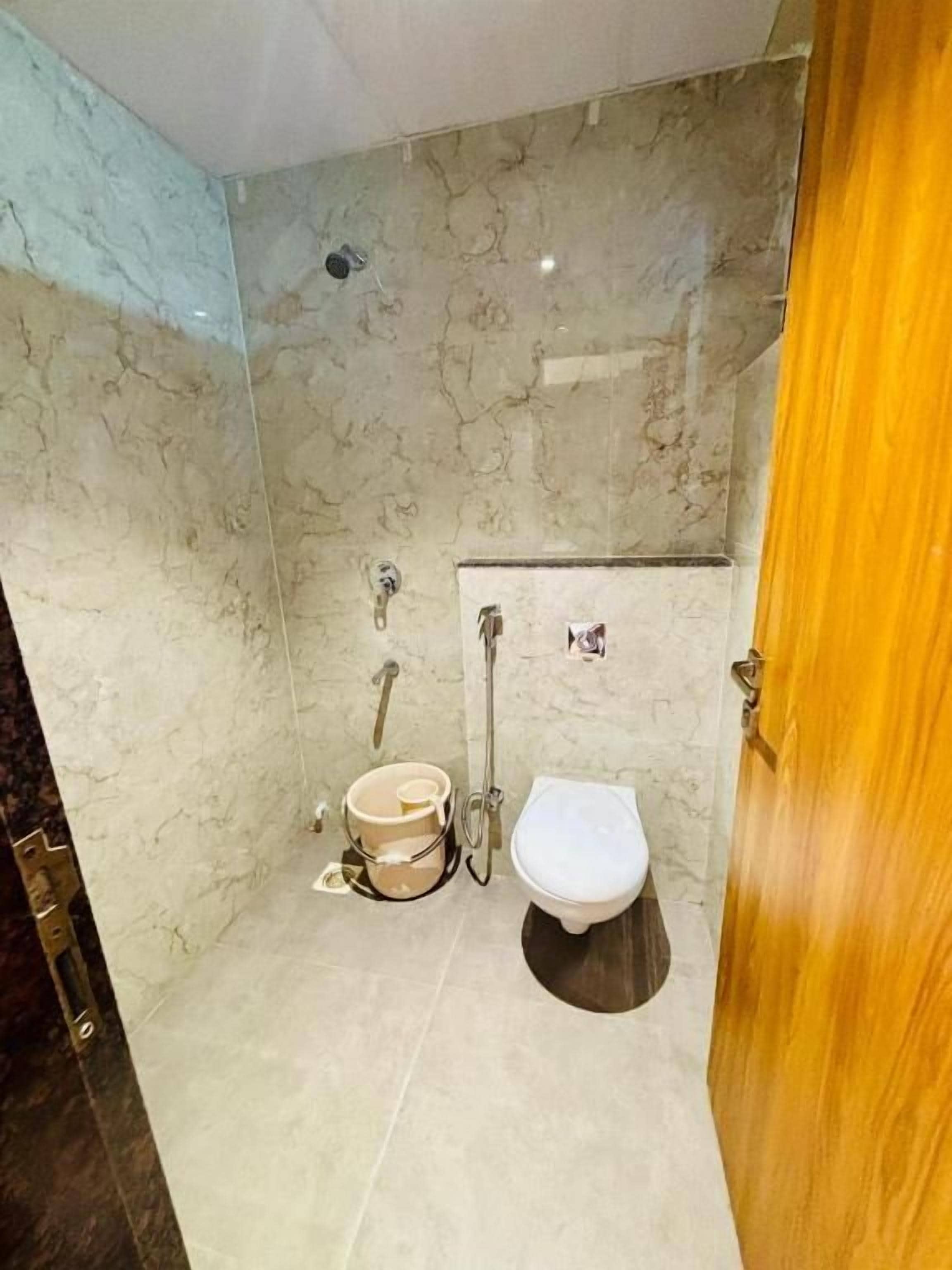 A bathroom with a toilet, a shower, and a marble wall.