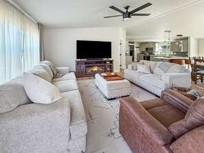 A modern living room with a fireplace, sofas, and a television. - Your Mountain Adventure Awaits | Hot Tub + Minutes to Tamarack (Donnelly)