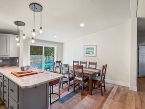 A modern kitchen with a large island, dining area, and a view of the outdoors. - Your Mountain Adventure Awaits | Hot Tub + Minutes to Tamarack (Donnelly)