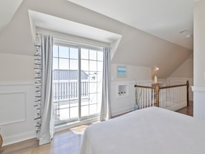 A bedroom with a large window, a wooden staircase, and a view of a balcony. - Harbor-View Condo w/ Sun Deck near Cape May (Cape May)