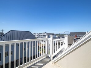Ein Wohngebiet mit weißem Balkonläufer, grauem Dach und blauem Himmel.