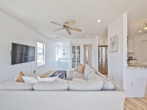 A modern living room with a sectional sofa, a flat-screen TV, and a ceiling fan. - Harbor-View Condo w/ Sun Deck near Cape May (Cape May)