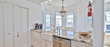 A modern kitchen with white cabinetry, a stainless steel dishwasher, and a granite countertop.