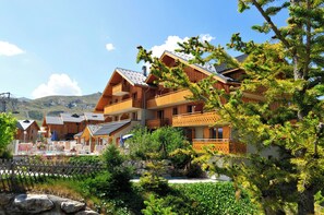 Un chalet en bois doté de balcons, d’un espace piscine et surplombant un paysage montagneux.