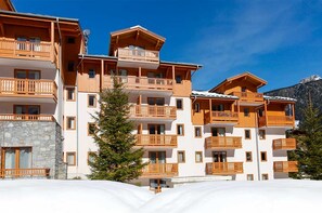 A multi-story hotel with balconies, a stone facade, and a mountainous backdrop. - Au cœur du Parc de la Vanoise | Piscine sur place (Pralognan-la-Vanoise)