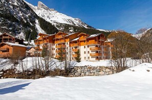 A cluster of wooden chalets with balconies, set against a backdrop of snow-covered mountains. - T2 à l’entrée de la station | Piscine couverte (Pralognan-la-Vanoise)