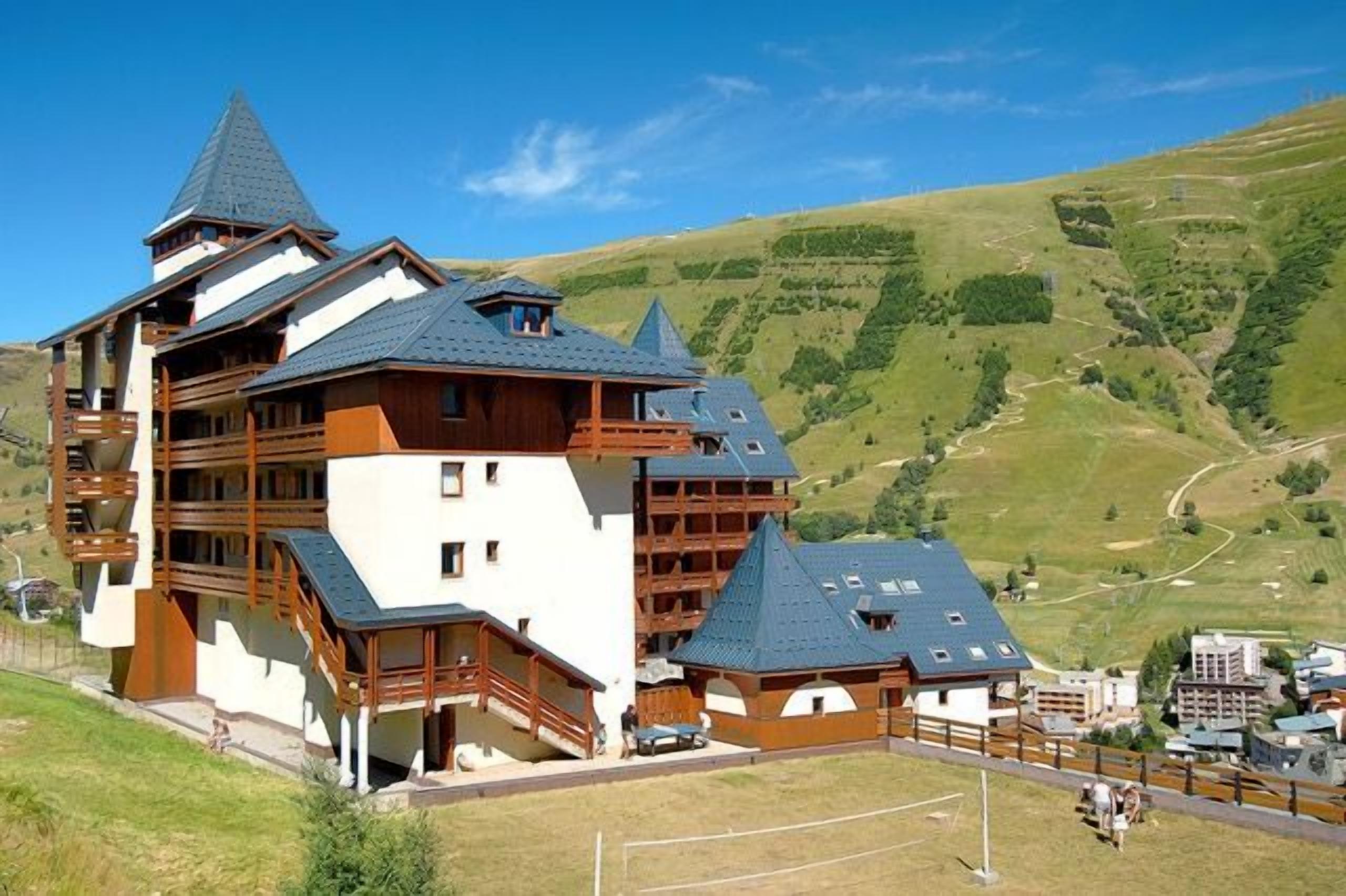 Un edificio de varios pisos con balcones, con montañas al fondo.