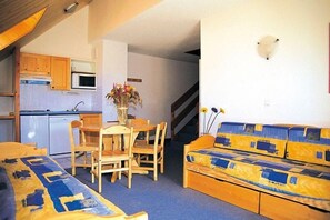 Un espace de vie compact comprenant une kitchenette, un coin repas et un canapé.